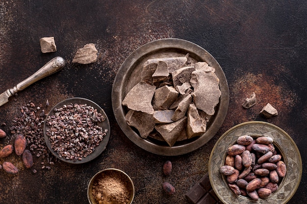 Free photo flat lay of chocolate chunks on plate with cocoa powder and beans