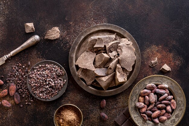 Flat lay of chocolate chunks on plate with cocoa powder and beans