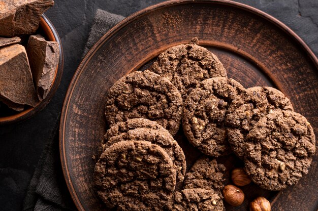 Flat lay of chocolate cookies on plate with hazelnuts