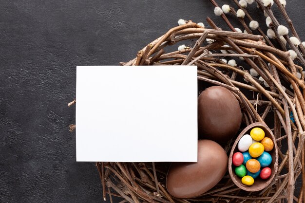 Flat lay of chocolate easter eggs filled with colorful candy in nest