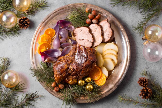 Flat lay of christmas steak on plate with globes and pine cones decor