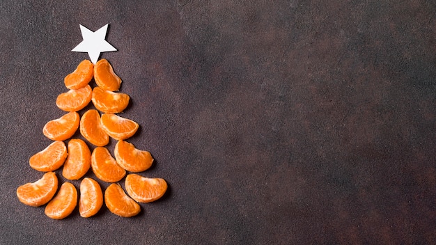 Flat lay of christmas tree shape make of tangerines with copy space