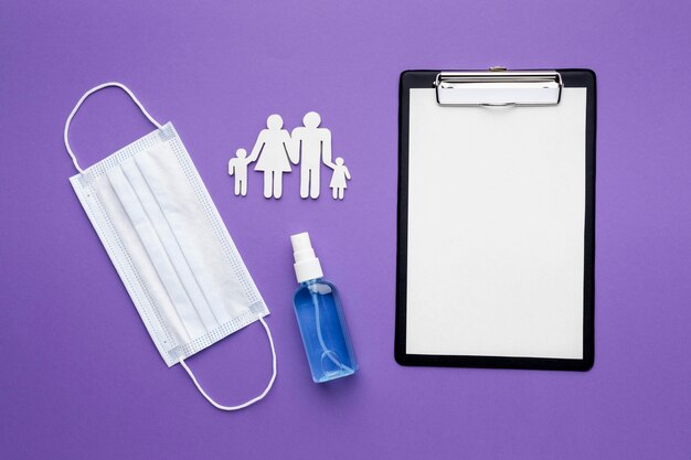 Flat lay of clipboard with medical mask and family made of paper