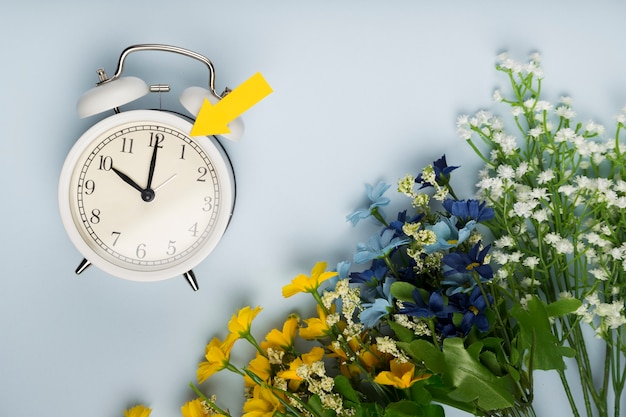 Flat lay clock beside bouquet of flowers