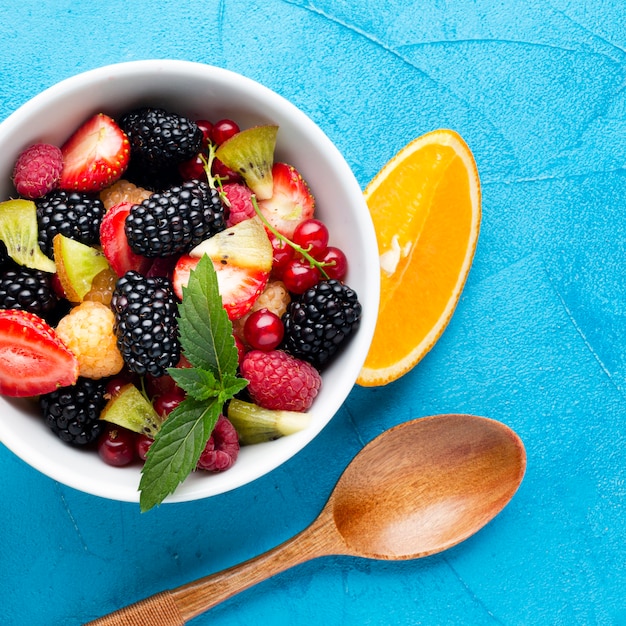 Плоская миска из свежих ягод и фруктов с ложкой