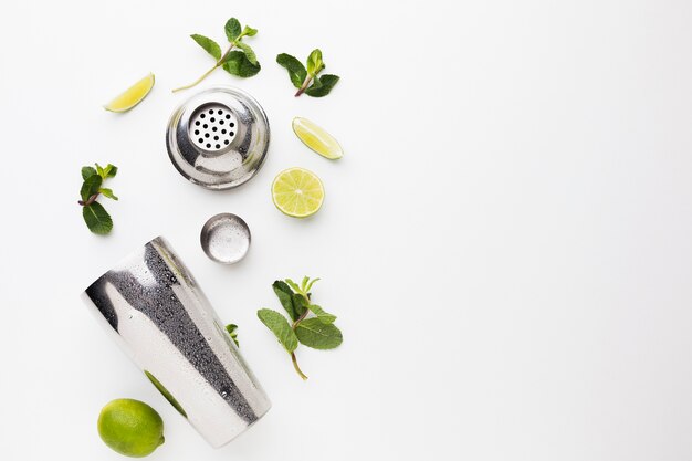 Flat lay of cocktail ingredients with shaker and lime slices