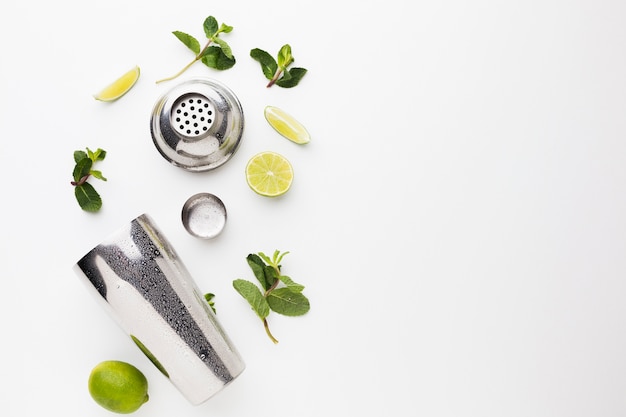 Flat lay of cocktail ingredients with shaker and lime slices