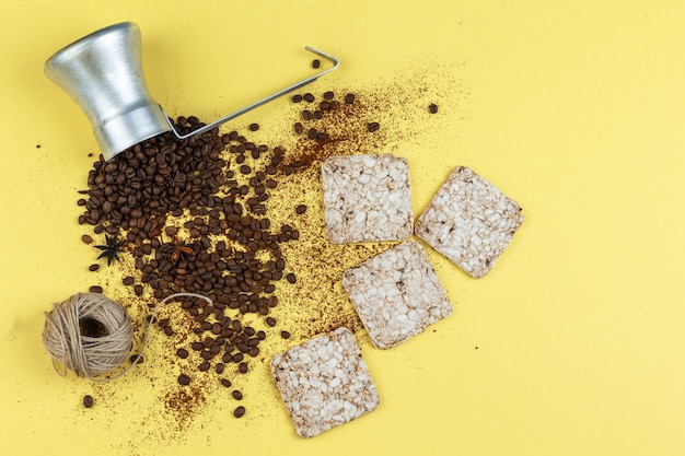 Flat lay coffee beans in jug with rice cakes, ropes on yellow background. horizontal