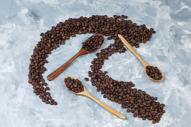 Flat lay coffee beans in wooden spoons on grey plaster background. horizontal