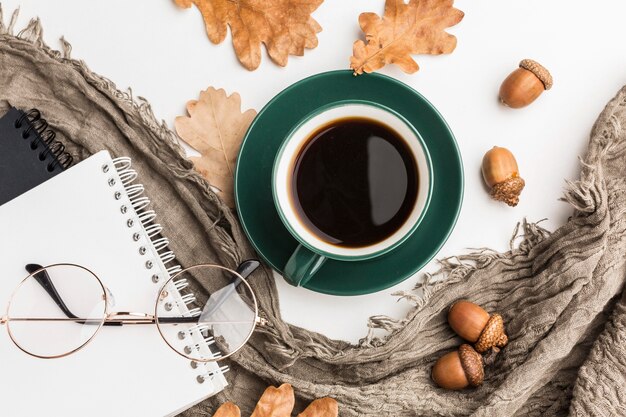 Flat lay of coffee cup with autumn leaves and notebooks