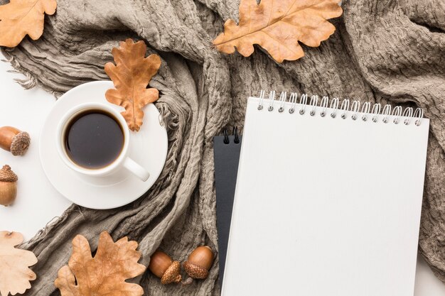 Flat lay of coffee cup with textile and autumn leaves