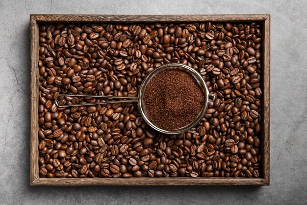 Flat lay coffee powder in strainer on coffee beans