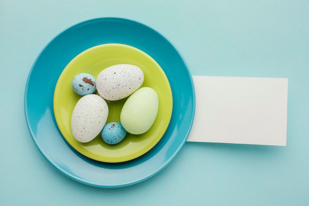 Flat lay of colored easter eggs on plates with paper