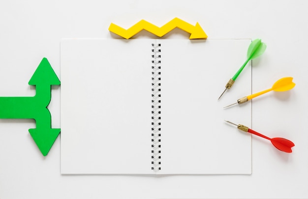 Free photo flat lay colorful arrows and notebook mock-up