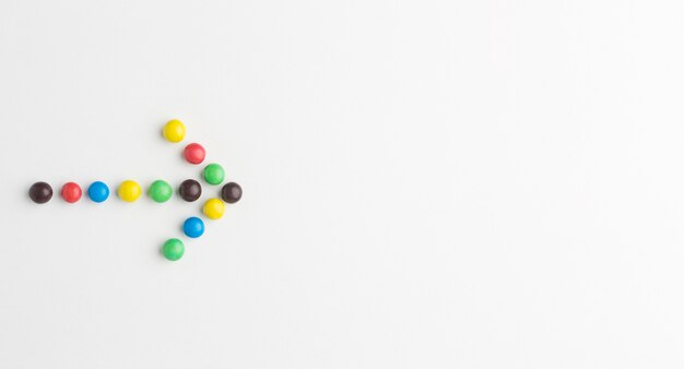 Flat lay of colorful candy arrow with copy space