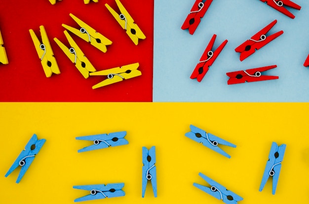 Flat-lay colorful clothes pins on colored backgrounds