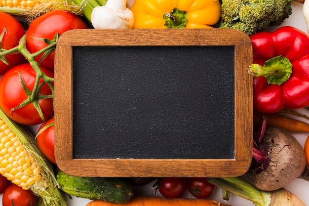 Flat lay colorful composition of vegetables with blackboard