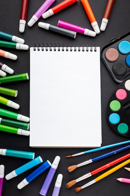 Flat lay of colorful markers with notebook