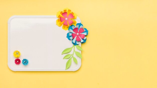 Flat lay of colorful paper flowers on whiteboard