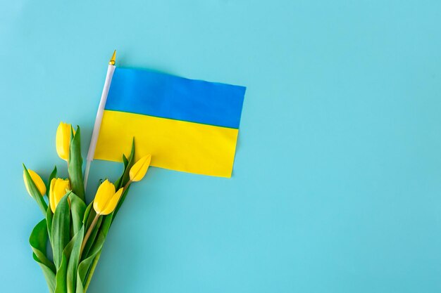 黄色いチューリップの花束とウクライナの旗とフラットレイ構成