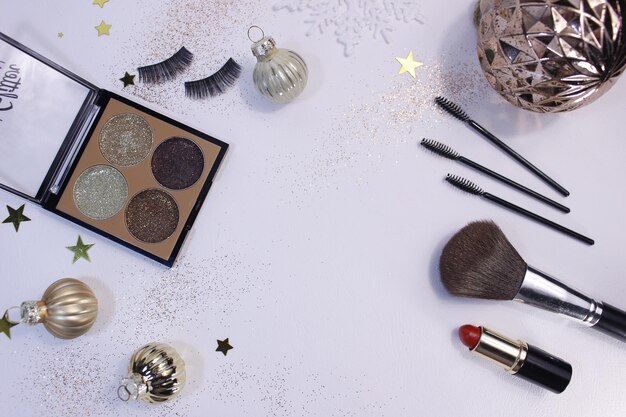 Flat lay composition with makeup products and christmas decor on white background. template for design, top view flat lay copy space.