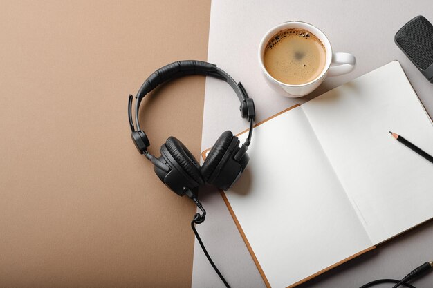 Flat lay composition with Microphone for podcasts and black studio headphones on brown background with coffee and laptop learning online education concept