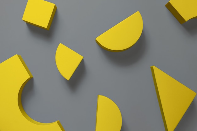 Flat lay composition of yellow geometric shapes on ultimate gray surface. colors of the year 2021