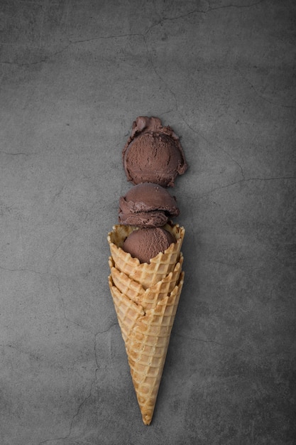 Free photo flat lay cone with three scoops of chocolate ice cream
