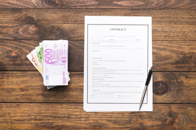 Flat lay contract with money on wooden table