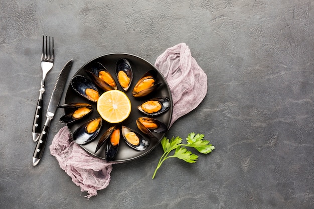 Flat-lay cooked mussels plate with cutlery