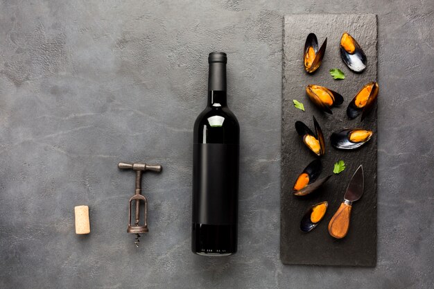 Flat-lay cooked mussels on slate with wine bottle