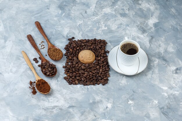 フラットレイクッキー、コーヒー豆とコーヒー、インスタントコーヒー、水色の大理石の背景に木のスプーンでコーヒー粉。水平