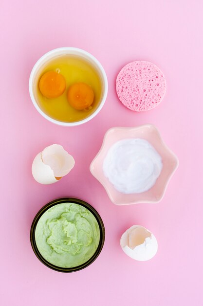 Flat lay of cream and eggs on pink background