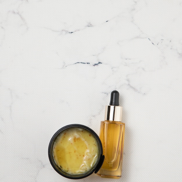 Free photo flat lay of cream and essential oil bottle on marble background