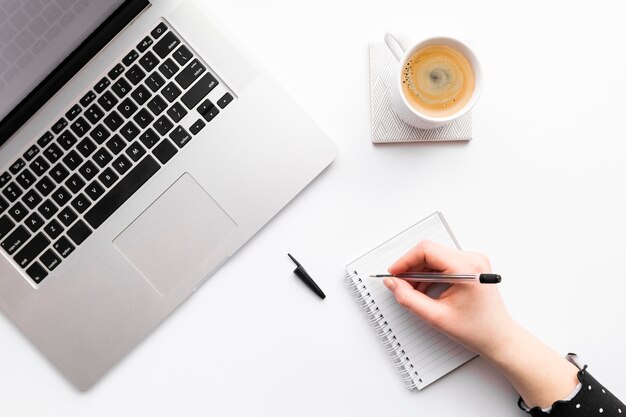 Flat lay creative business arrangement on white background with person taking notes