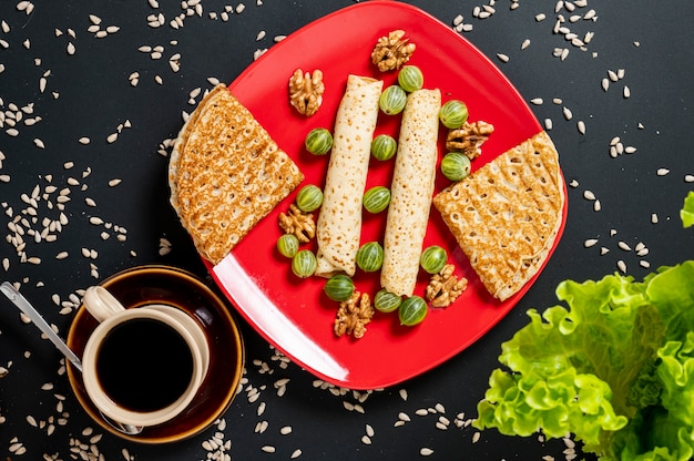 Free photo flat lay crepes arrangement with cup of coffee on plain blackground