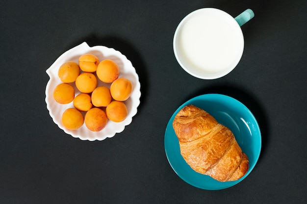 Flat lay croissant, milk and apricots on plain background