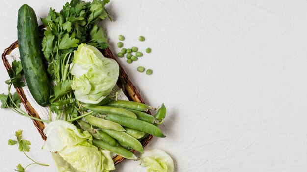 Flat lay of cucumber and assortment of vegetables in basket