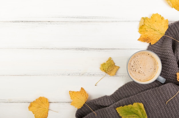 Flat lay cup of coffee and autumn leaves with copy space