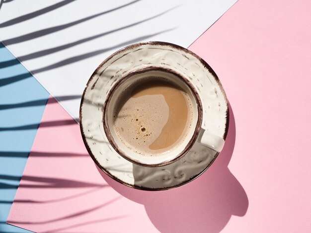 Flat lay cup of coffee on pink background