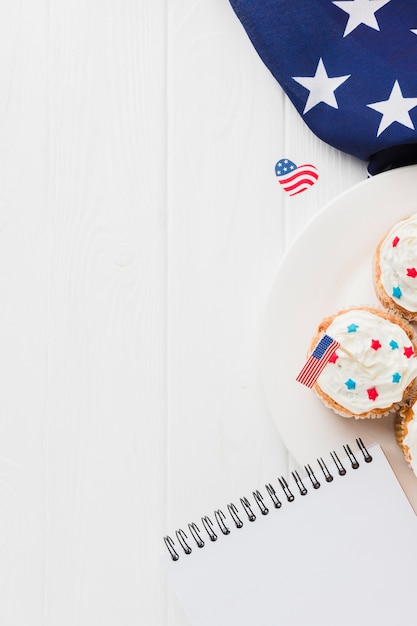 アメリカの国旗とノートとカップケーキのフラットレイアウト