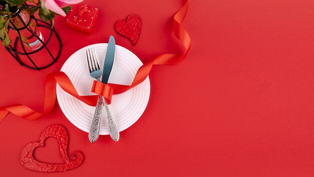 Flat lay of cutlery on plate with ribbon and hearts