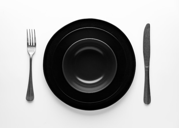 Flat lay of dark dinnerware with cutlery