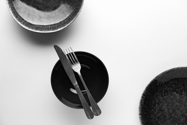 Flat lay of dark dinnerware with knife and fork