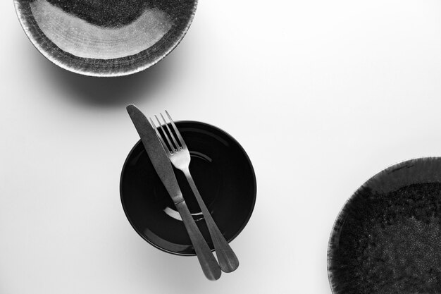 Flat lay of dark dinnerware with knife and fork