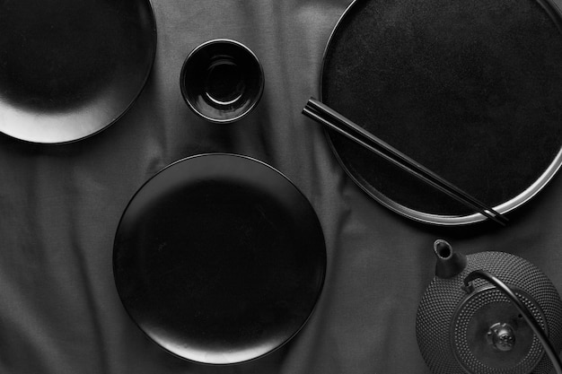 Плоский набор темных тарелок и палочек для еды