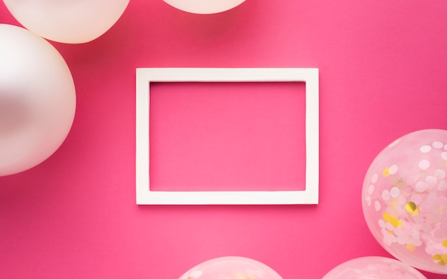 Flat lay decoration with balloons, frame and pink background