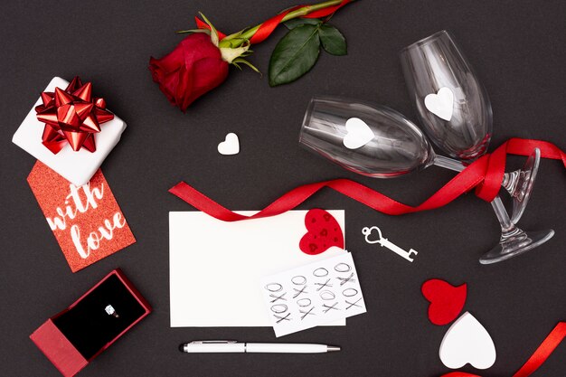 Flat lay decoration with glasses and gift on black background