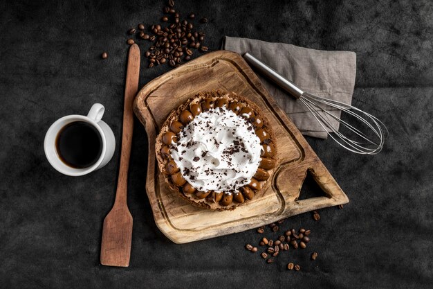 Flat lay of delicious cake with whisk and coffee