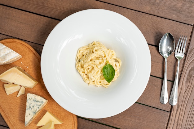 Flat lay of delicious carbonara pasta on wooden table